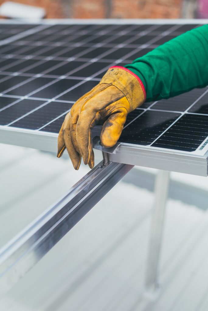 smutsig handske över solceller som symboliserar energioptimering